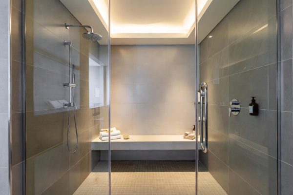 Elegant walk-in shower with frameless glass, bench seating, and rainfall showerhead, high-end spa aesthetic